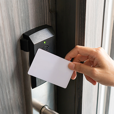 a person using a key card to open a smart lock on a dark wooden door 