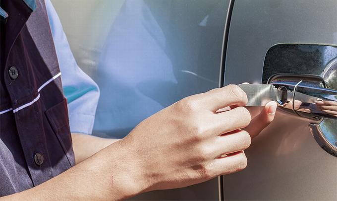 a locksmith using specialist tools to open a black car door